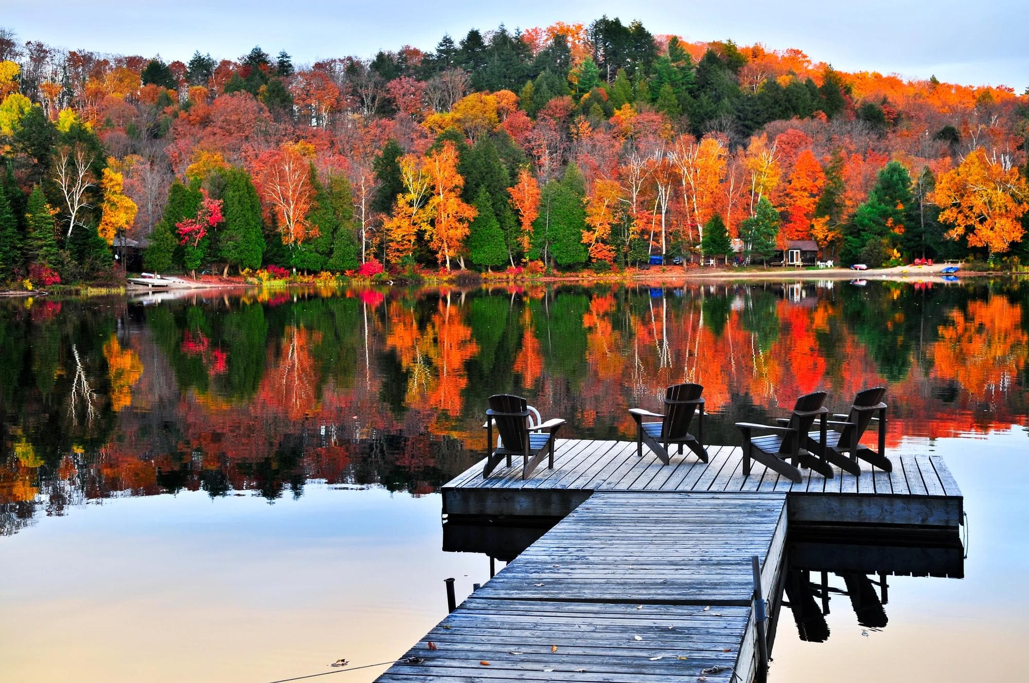 dock and deck chairs by the lake with autumnal forest