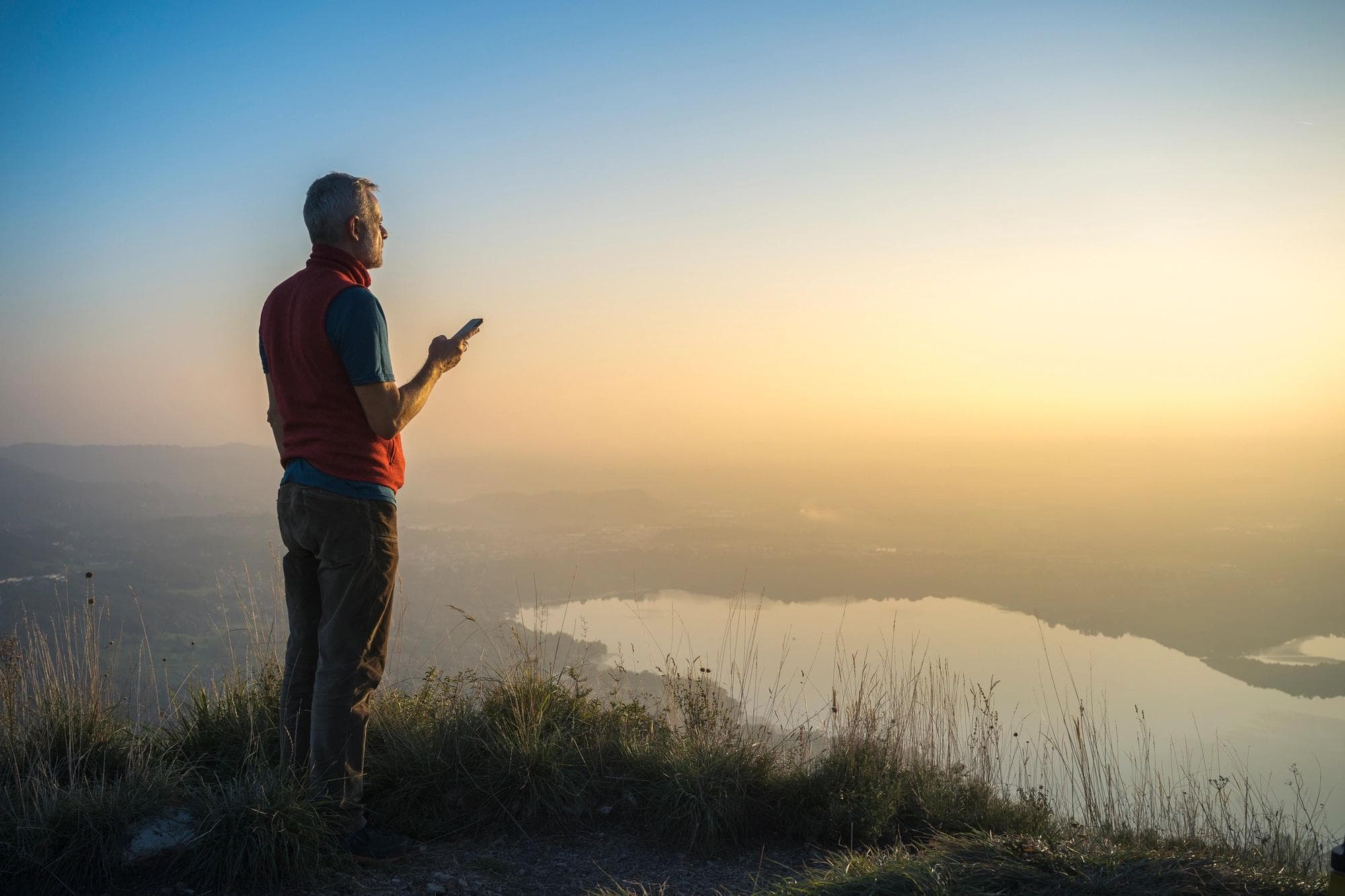 person standing on top of a hill on phone