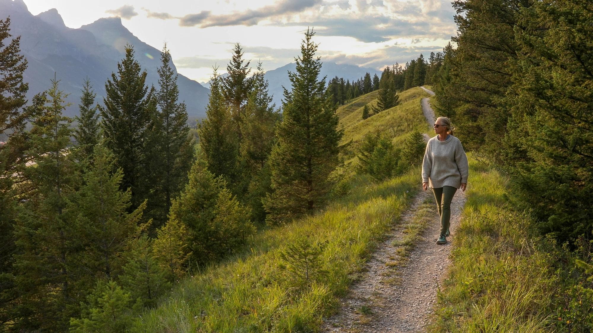 Mature woman walks down trail in the morning