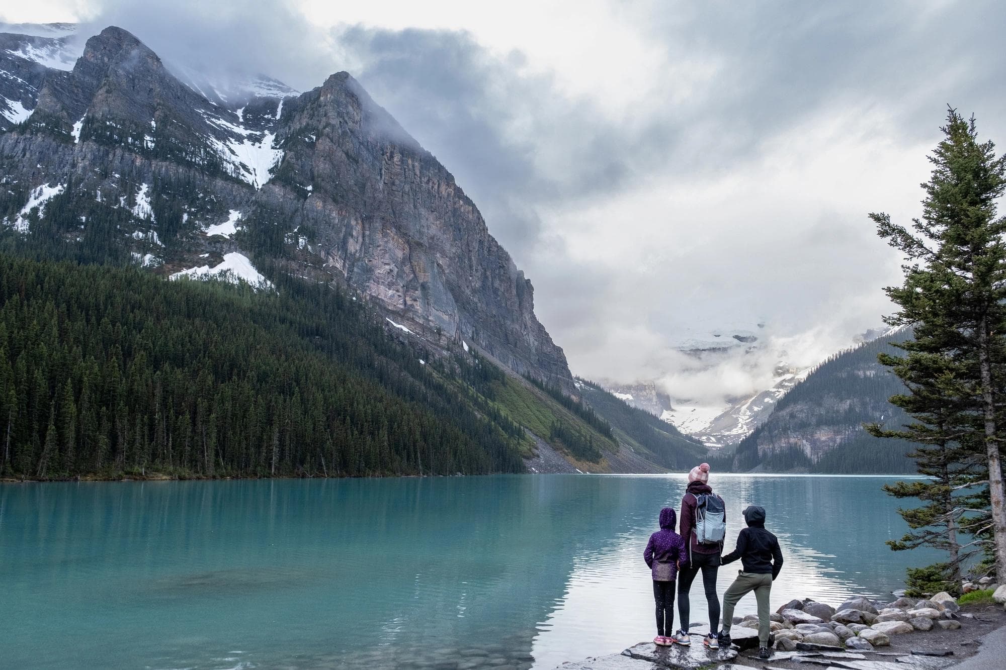 Family hiking around a pristine glacial lake in Banff National Park