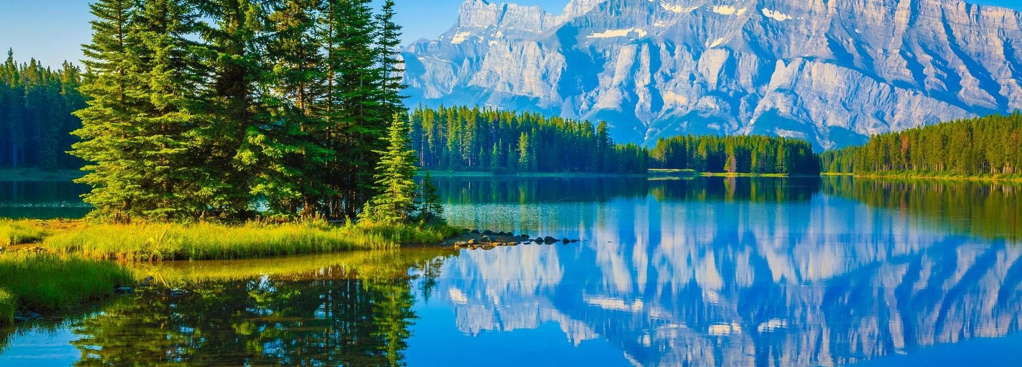 A lake by the forest with mountains