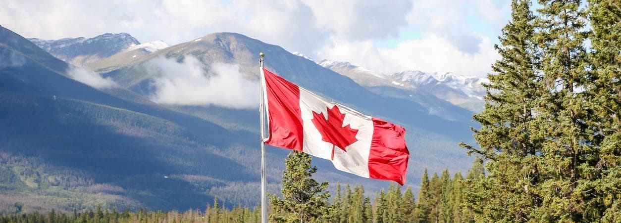 canadian flag with mountain and lake in background