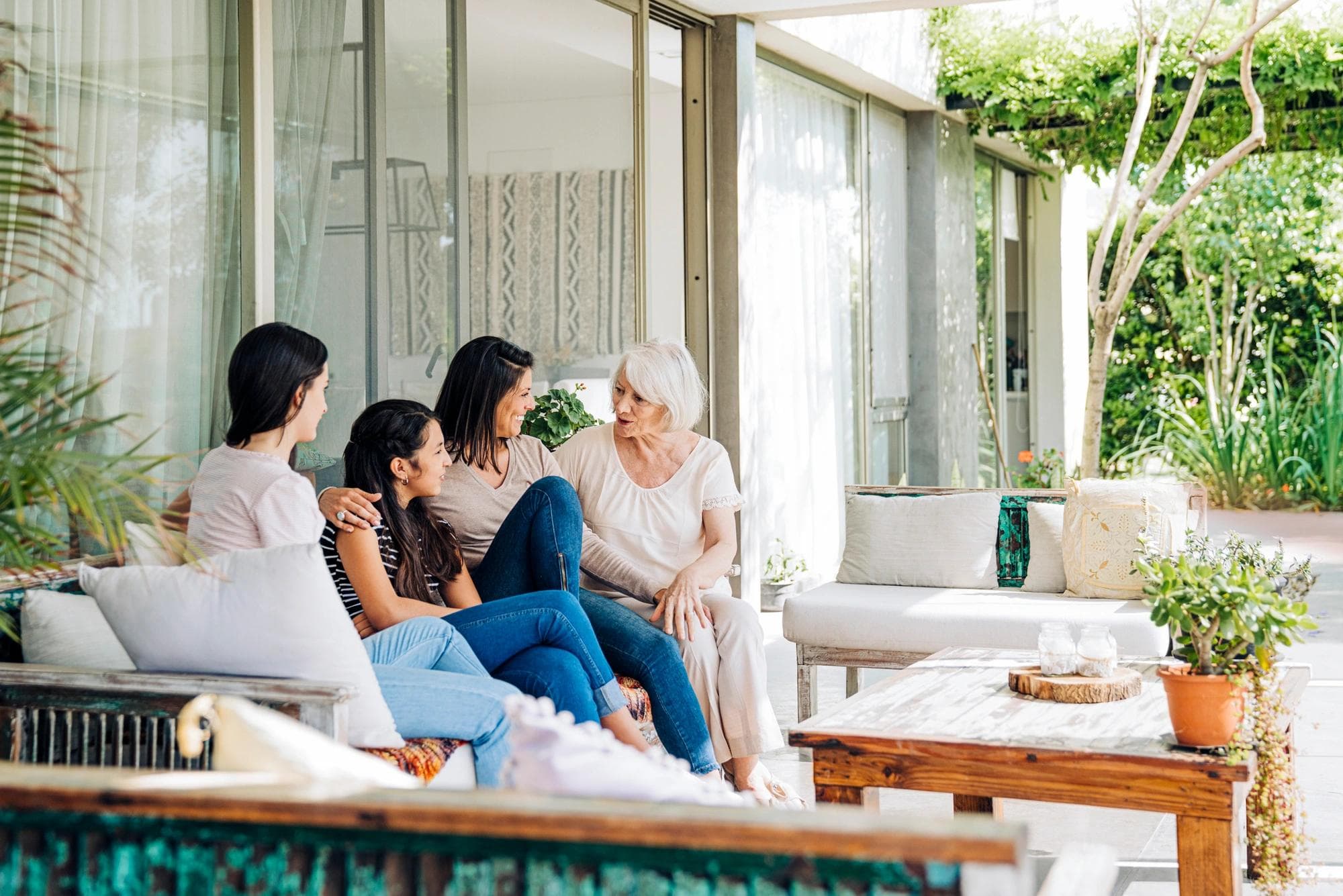 intergenerational family sitting on bench talking outdoors